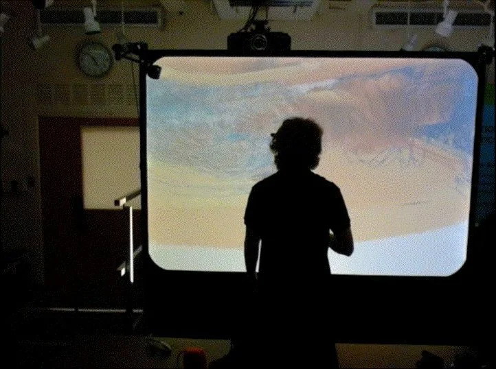 A silhouetted visitor in front of the CAVE projection screen
